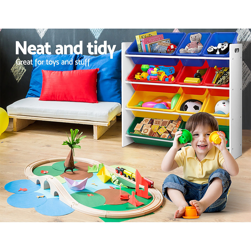 A toddler sits smiling and happy in a clean room with toys neatly and safely stored in a stylish storage unit with easy access bins full of toys.